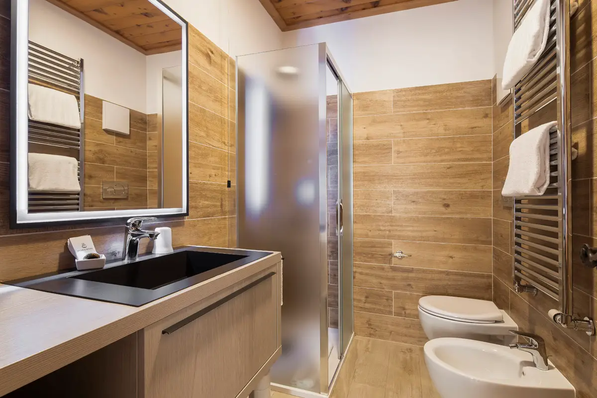 Bagno moderno della camera Superior Tripla con doccia e finiture in legno – Hotel Montana Cortina. | Modern bathroom of the Superior Triple Room with shower and wood finishes – Hotel Montana Cortina.