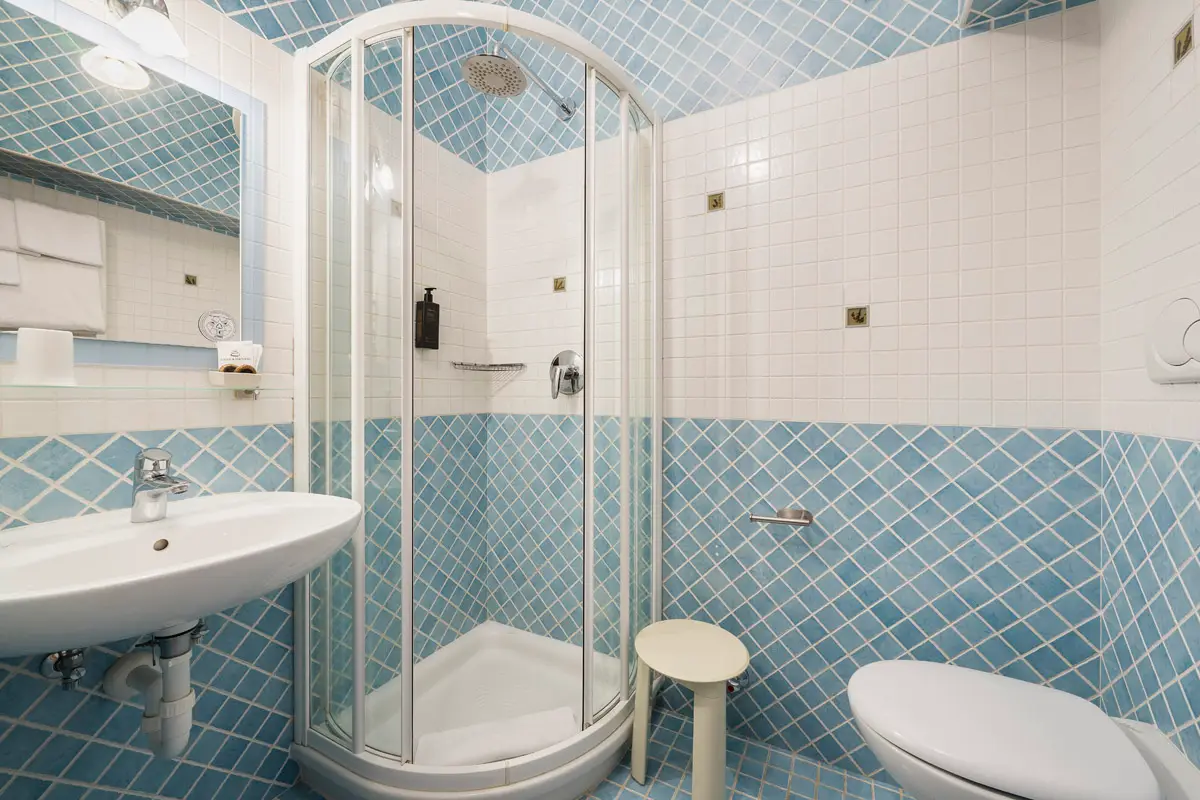 Bagno Classic Doppia — bagno con doccia e piastrelle azzurre, Hotel Montana Cortina. | Classic Double Bathroom — blue-tiled bathroom with shower, Hotel Montana Cortina.