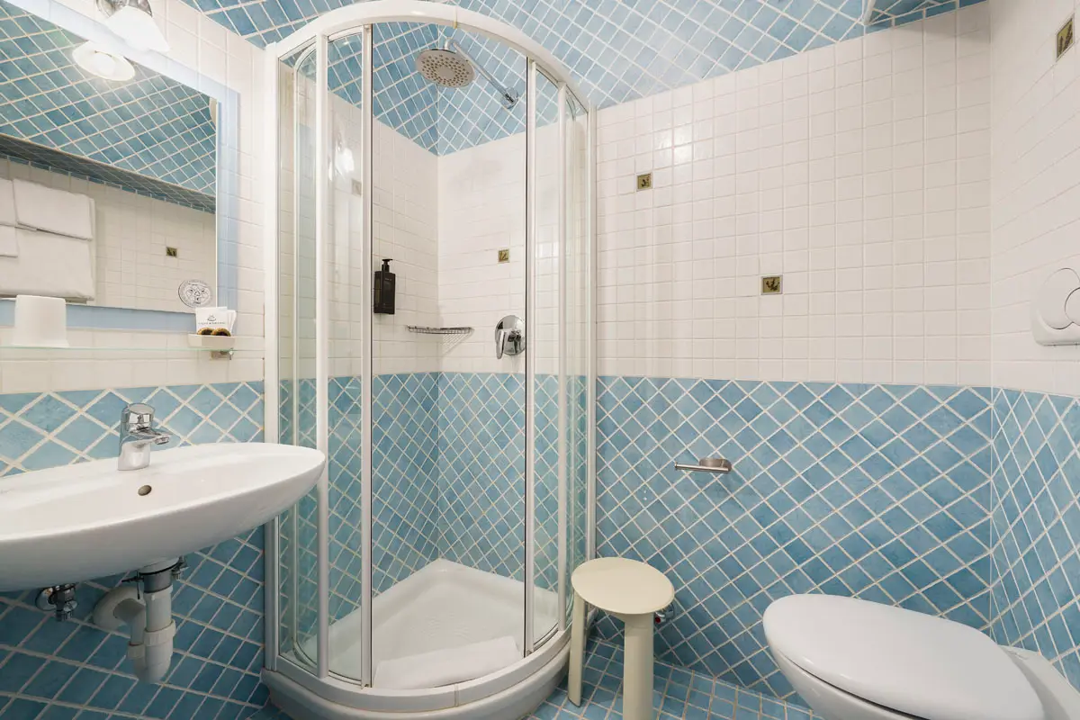Bagno Doppia Economy con doccia e piastrelle azzurre – Hotel Montana Cortina | Economy Double Room bathroom with blue tiles and shower – Hotel Montana Cortina