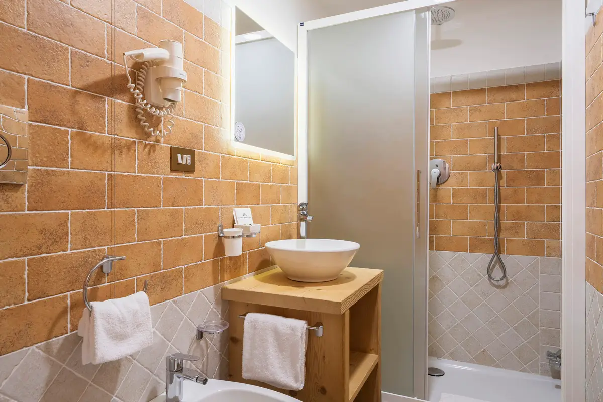 Bagno Singola Superior con lavabo e doccia in ceramica color terracotta. | Single Superior bathroom with terracotta ceramic shower and sink.