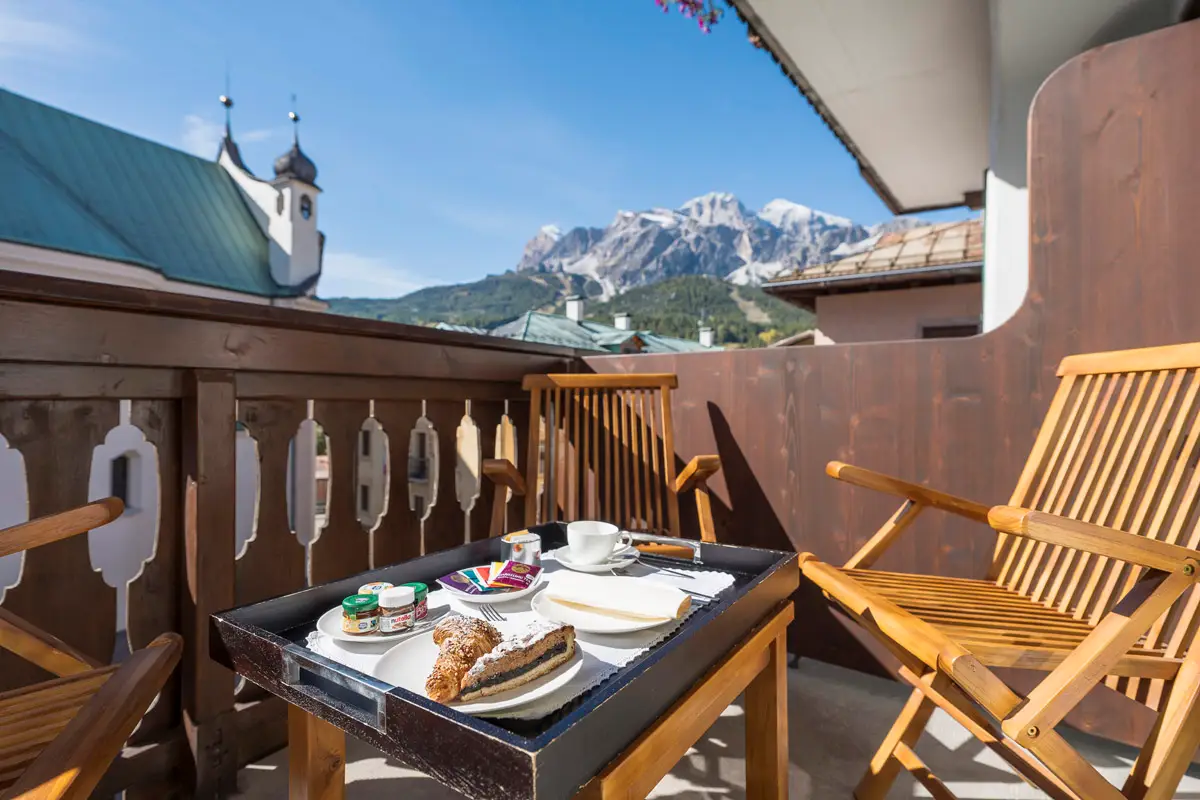 Balcone privato della camera Superior Tripla con vista Dolomiti – Hotel Montana Cortina. | Private balcony of the Superior Triple Room with Dolomites view – Hotel Montana Cortina.