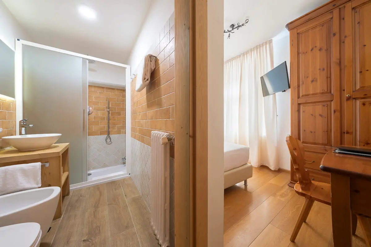 Camera Singola Superior con doccia e armadio in legno chiaro. | Single Superior room with shower and light-wood wardrobe.