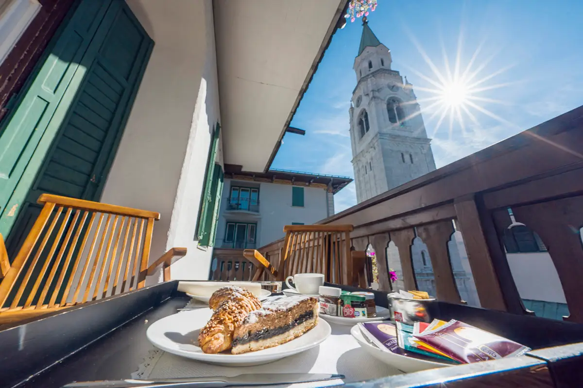 Colazione servita sul balcone della Superior Tripla con vista campanile – Hotel Montana Cortina. | Breakfast on the balcony of the Superior Triple Room with bell tower view – Hotel Montana Cortina.