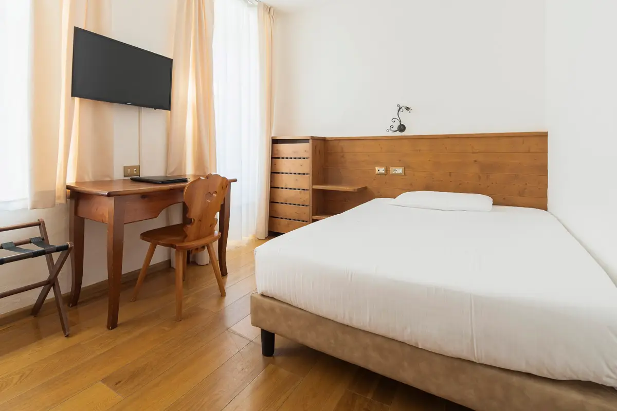 Camera Singola Superior con letto e scrivania in stile alpino. | Single Superior room with bed and alpine-style desk.