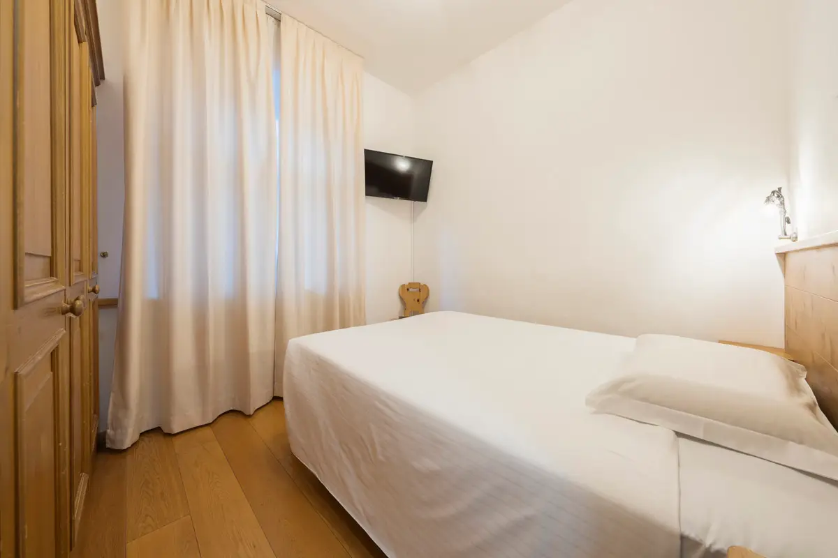 Camera Singola Superior con letto alla francese e tende luminose. | Single Superior room with French bed and bright curtains.