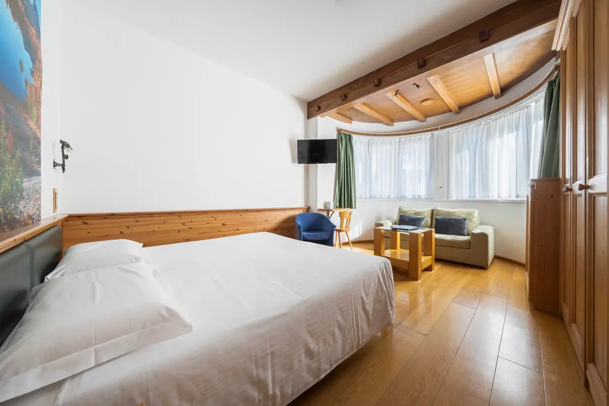 Camera Superior Tripla ampia e luminosa con vista centro – Hotel Montana Cortina. | Bright and spacious Superior Triple Room with town view – Hotel Montana Cortina.