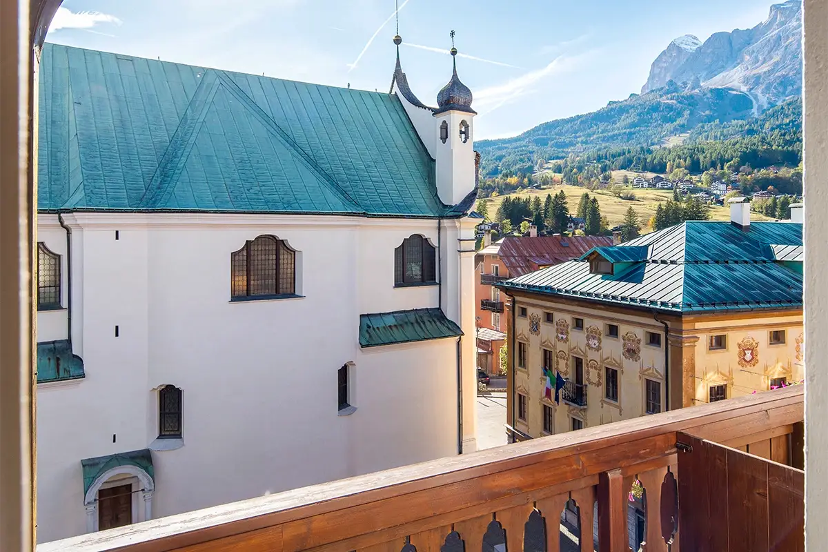 Balcone della Family Room con vista sulle Tofane e zona relax in legno a Cortina d'Ampezzo. | Family Room balcony with view of the Tofane mountains and wooden relaxation area in Cortina d'Ampezzo.