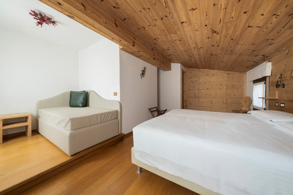 Camera mansardata Superior Tripla con travi in legno – Hotel Montana Cortina. | Attic-style Superior Triple Room with wooden beams – Hotel Montana Cortina.