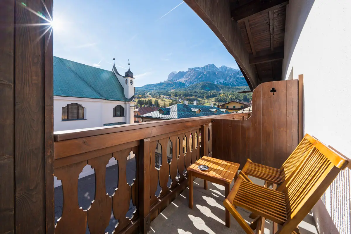 Terrazza della Family Room con affaccio sulle Dolomiti e sedute in legno. | Family Room terrace overlooking the Dolomites with wooden seating.