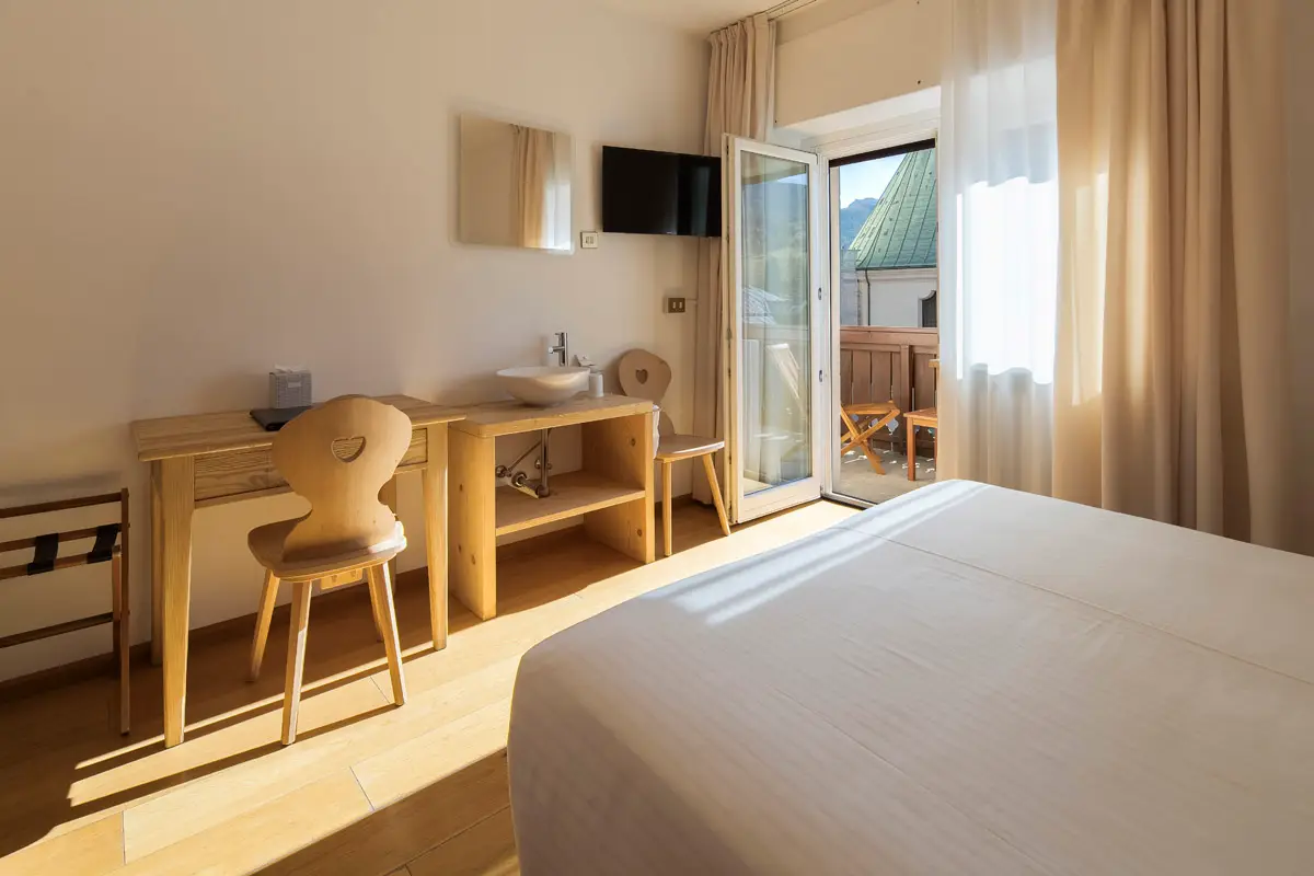 Camera Family luminosa in stile alpino, con scrivania e accesso diretto al balcone. | Bright alpine-style Family Room with desk and direct access to the balcony.