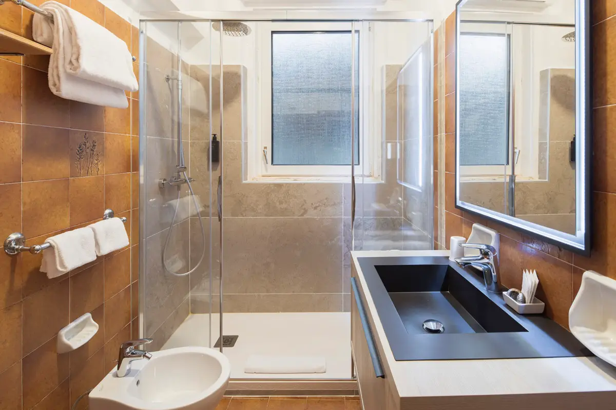Bagno della camera Superior Tripla con doccia e grande specchio – Hotel Montana Cortina. | Superior Triple Room bathroom with shower and large mirror – Hotel Montana Cortina.