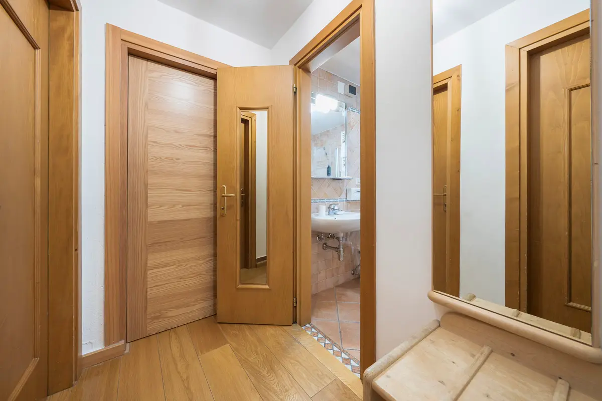 Ingresso della Family Room con pannellature in legno e accesso alle diverse stanze. | Family Room entrance with wooden paneling and access to different areas of the suite.